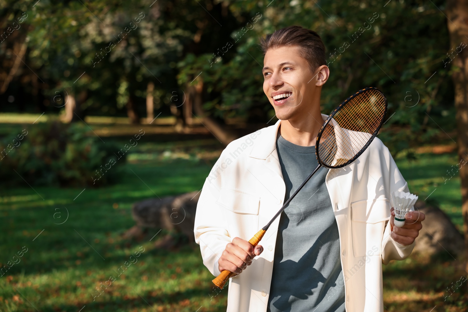 Photo of Happy young man with badminton racket and shuttlecock in park