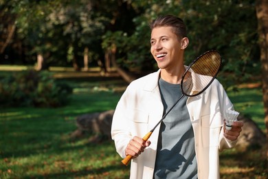 Photo of Happy young man with badminton racket and shuttlecock in park