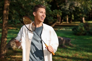 Photo of Happy young man with badminton racket and shuttlecock in park