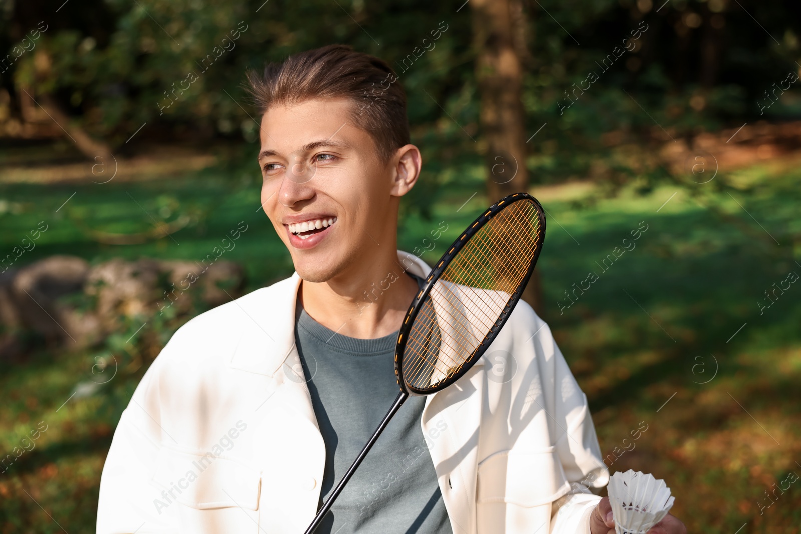 Photo of Happy young man with badminton racket and shuttlecock in park