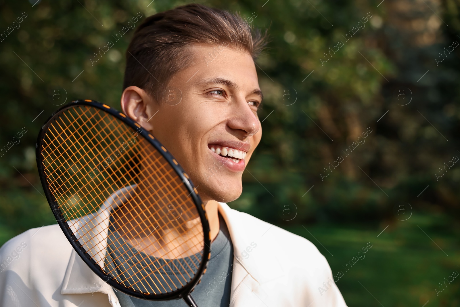 Photo of Happy young man with badminton racket in park