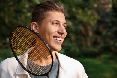 Photo of Happy young man with badminton racket in park