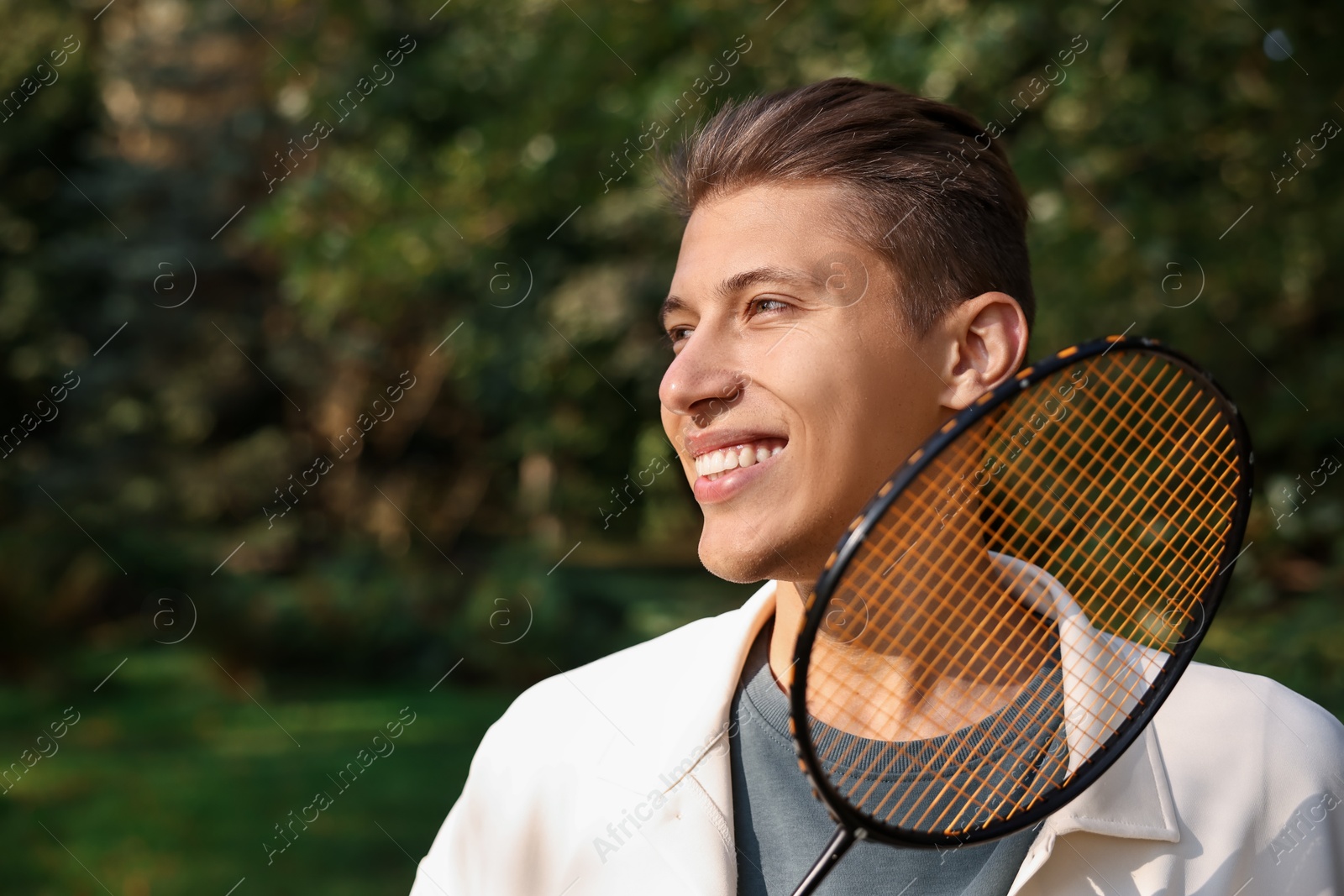 Photo of Happy young man with badminton racket in park