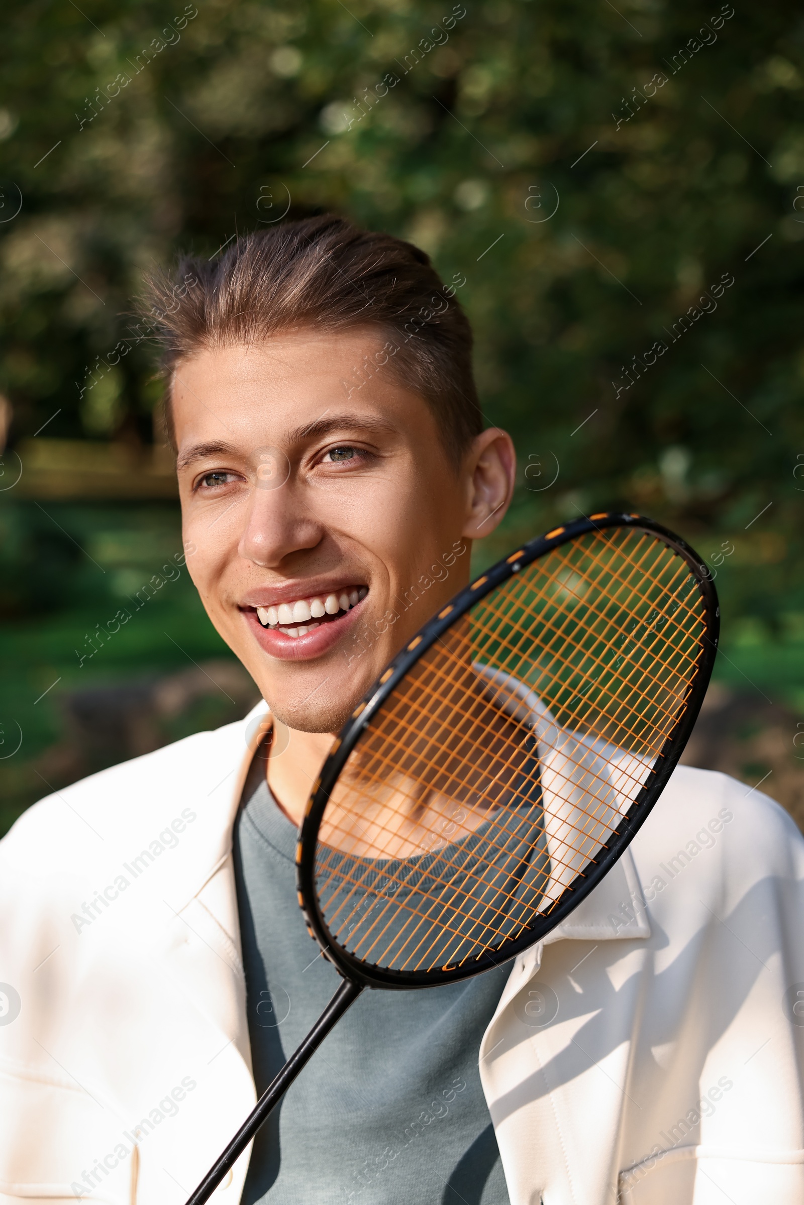 Photo of Happy young man with badminton racket in park