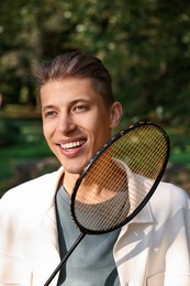 Photo of Happy young man with badminton racket in park