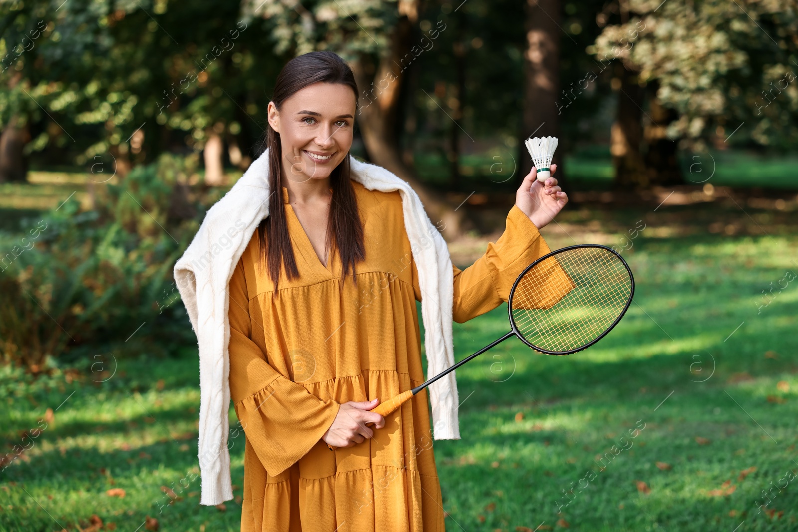 Photo of Happy young woman with badminton racket and shuttlecock in park