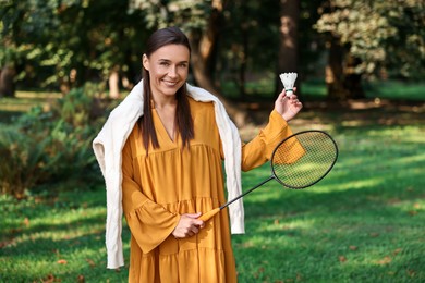 Photo of Happy young woman with badminton racket and shuttlecock in park