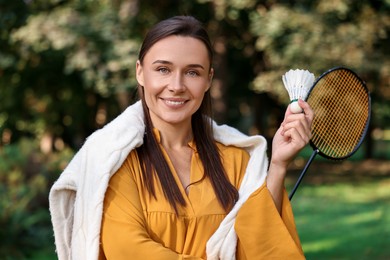 Photo of Happy young woman with badminton racket and shuttlecock in park