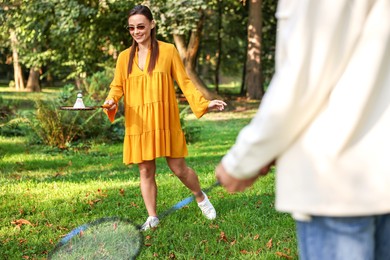 Photo of Young woman and man playing badminton in park, selective focus