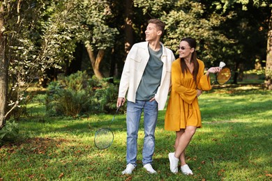 Photo of Young man and woman with badminton rackets and shuttlecock in park