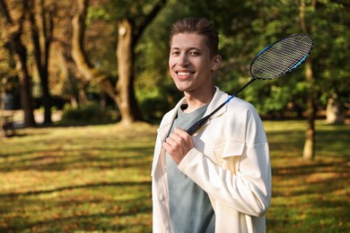 Photo of Happy young man with badminton racket in park