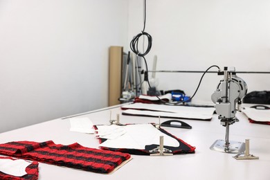 Photo of Professional workshop with different fabrics, white table and tools