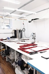 Photo of Professional workshop with different fabrics, white table and tools