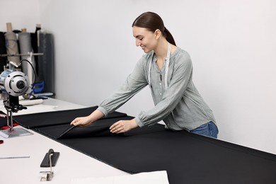 Young woman working at white table in professional workshop