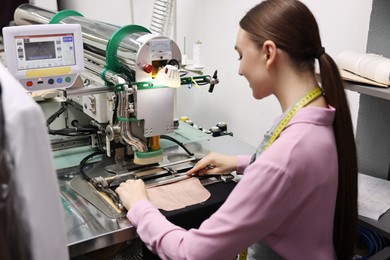 Photo of Young woman working with machine in professional workshop