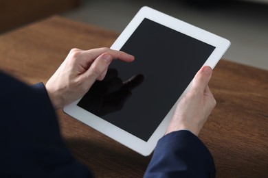 Photo of Businessman using tablet at wooden table, closeup. Modern technology