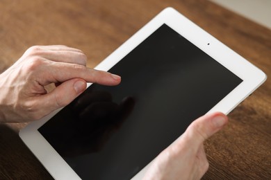 Photo of Businessman using tablet at wooden table, closeup. Modern technology