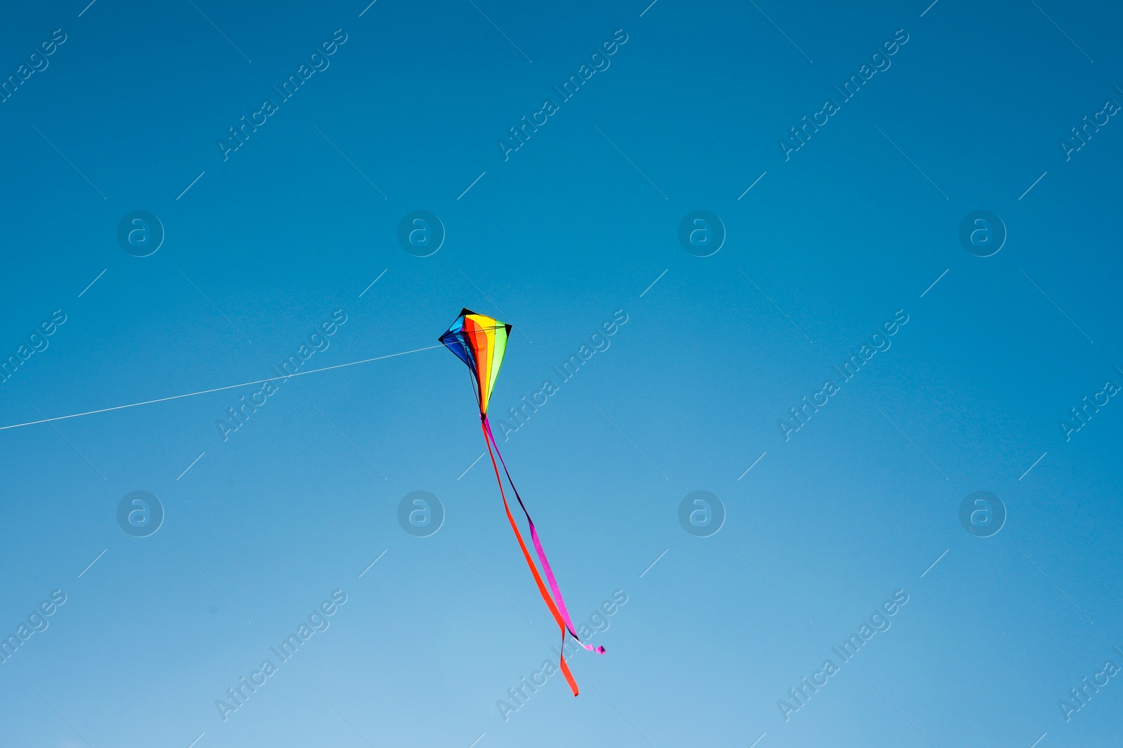 One colorful kite flying in blue sky. Space for text Photo of One colorful kite flying in blue sky. Space for text