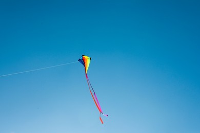 Photo of One colorful kite flying in blue sky. Space for text