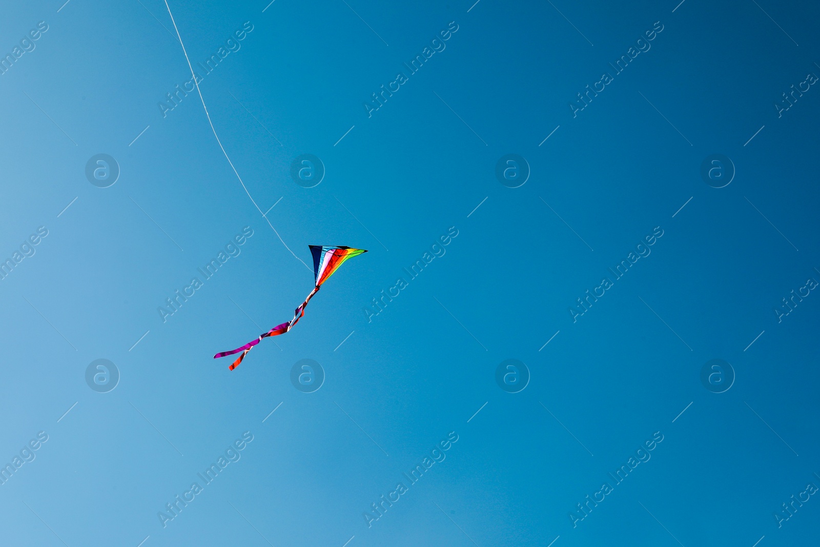One colorful kite flying in blue sky. Space for text Photo of One colorful kite flying in blue sky. Space for text