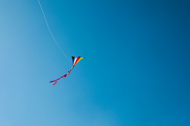 Photo of One colorful kite flying in blue sky. Space for text