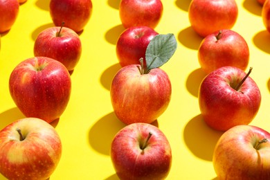 Many red apples on yellow background, closeup