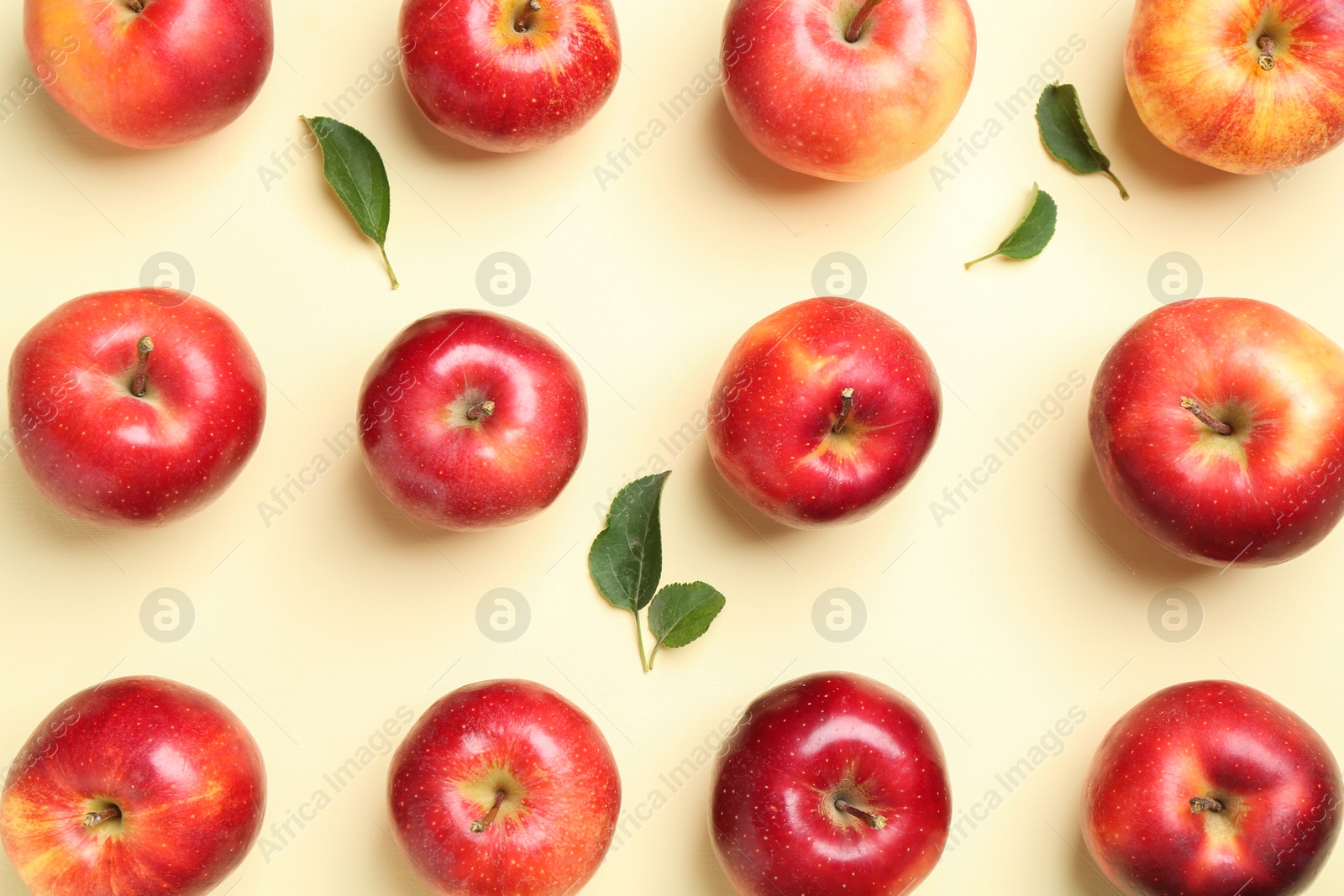 Photo of Many red apples and green leaves on beige background, flat lay