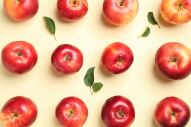 Many red apples and green leaves on beige background, flat lay