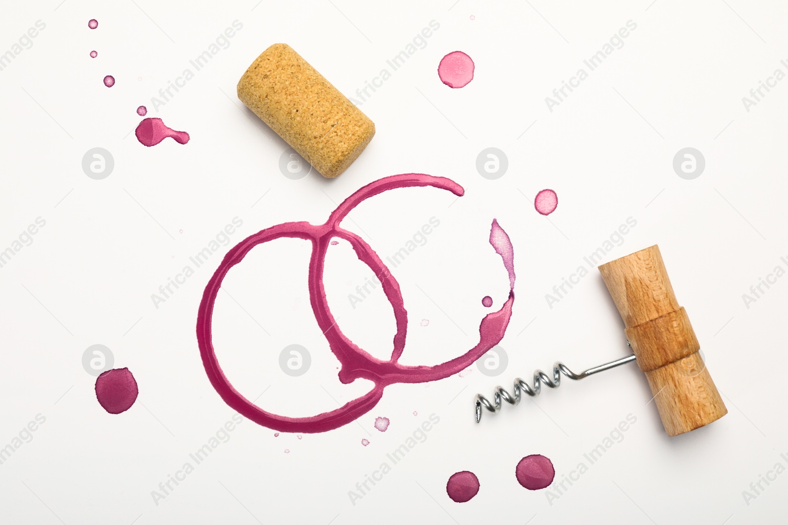 Photo of Corkscrew, cork and red wine stains on white background, top view