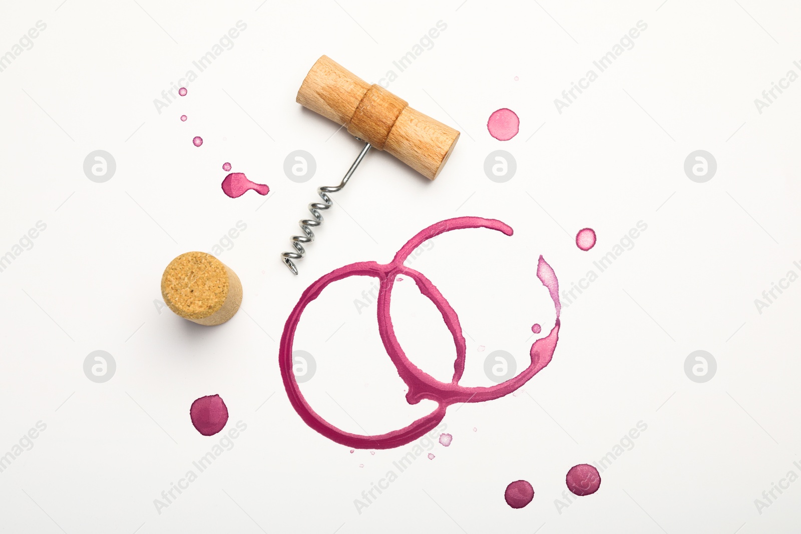 Photo of Corkscrew, cork and red wine stains on white background, top view