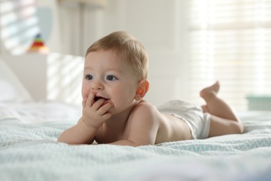 Photo of Cute little baby in diaper on bed at home