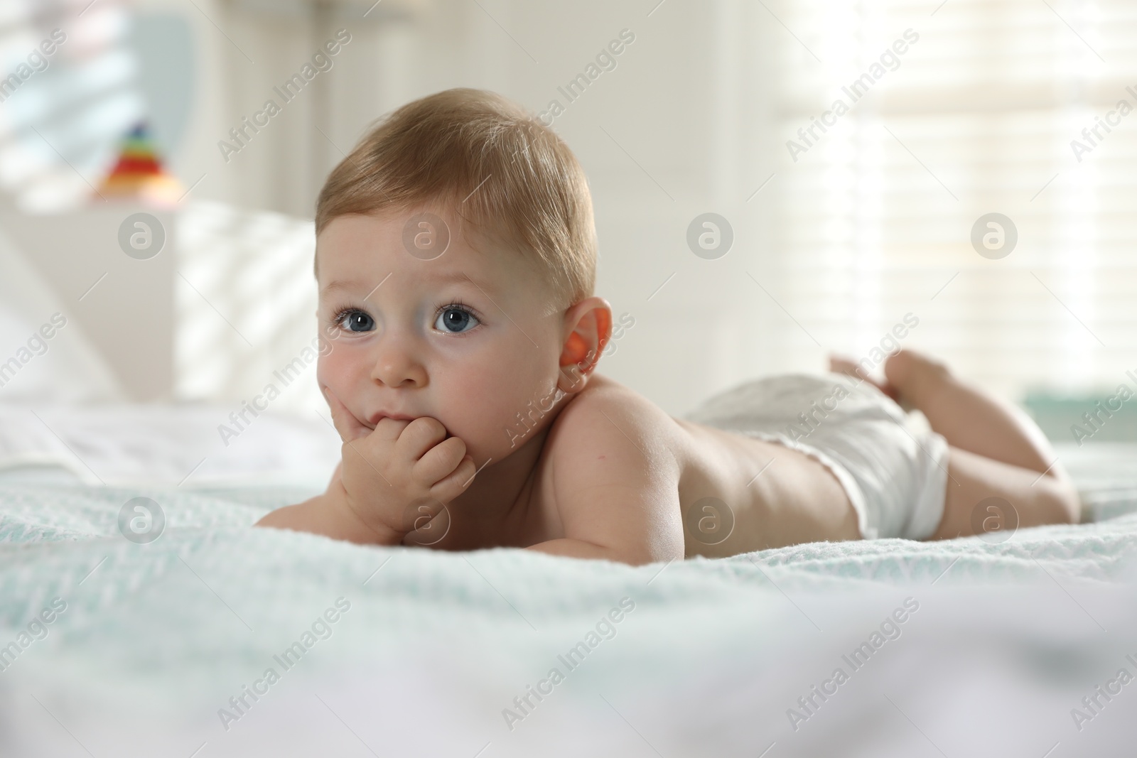 Photo of Cute little baby in diaper on bed at home