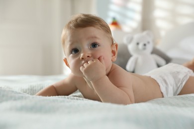 Photo of Cute little baby in diaper on bed at home