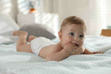 Cute little baby in diaper on bed at home