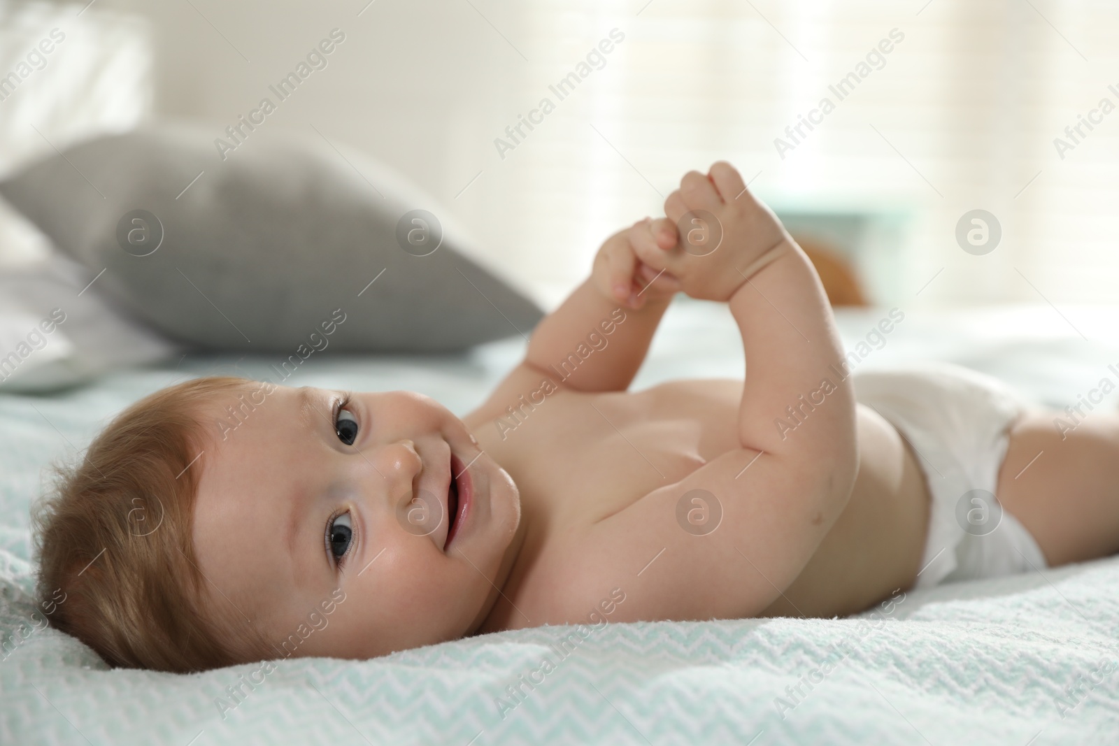 Photo of Cute little baby in diaper on bed at home