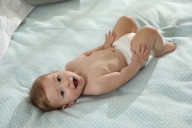 Photo of Cute little baby in diaper on bed at home