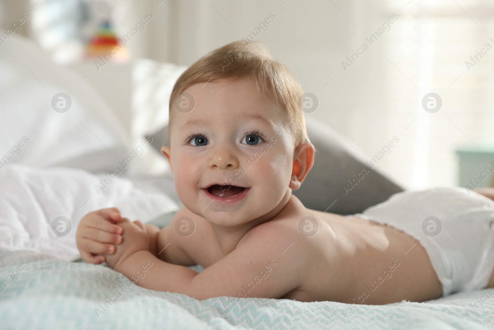 Photo of Cute little baby in diaper on bed at home