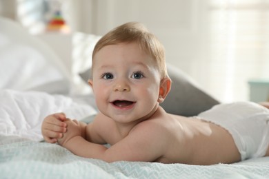 Photo of Cute little baby in diaper on bed at home