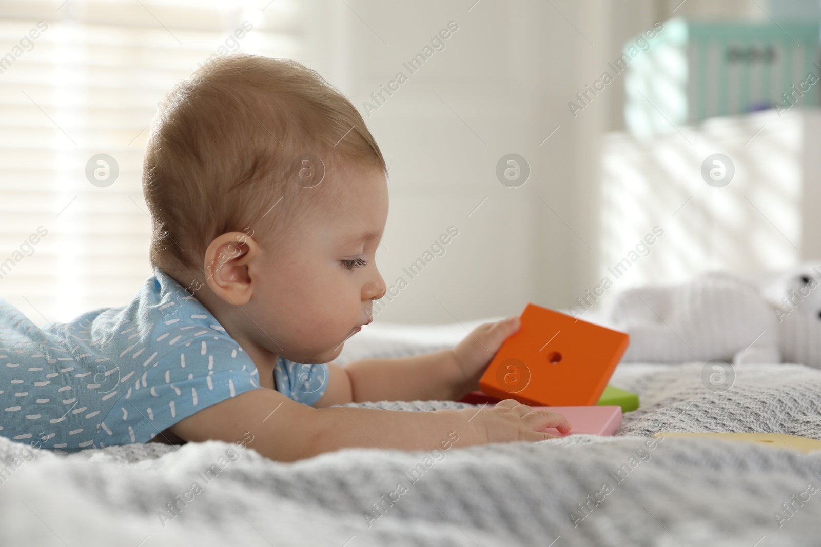 Photo of Cute little baby with toys on bed at home