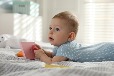 Photo of Cute little baby with toys on bed at home