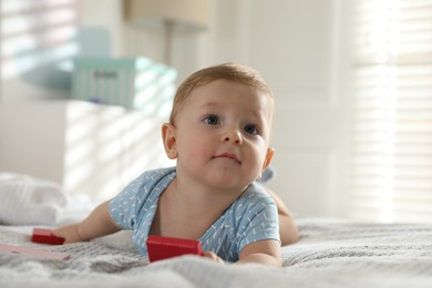 Photo of Cute little baby with toys on bed at home