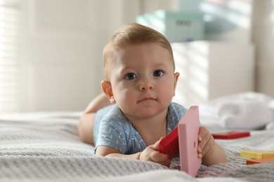 Photo of Cute little baby with toys on bed at home