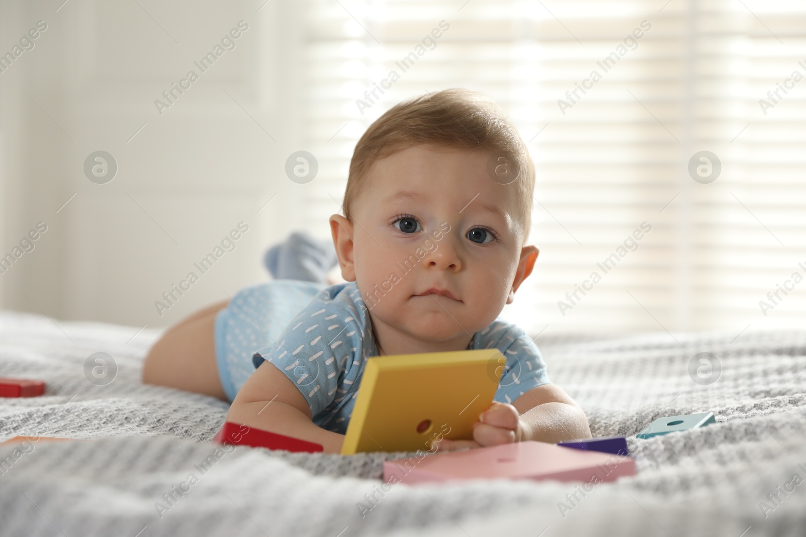 Photo of Cute little baby with toys on bed at home