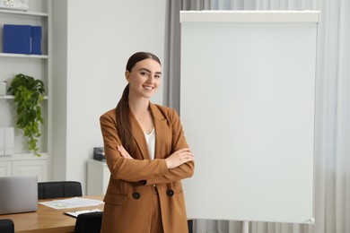 Photo of Happy woman near flip chart in office. Mockup for design