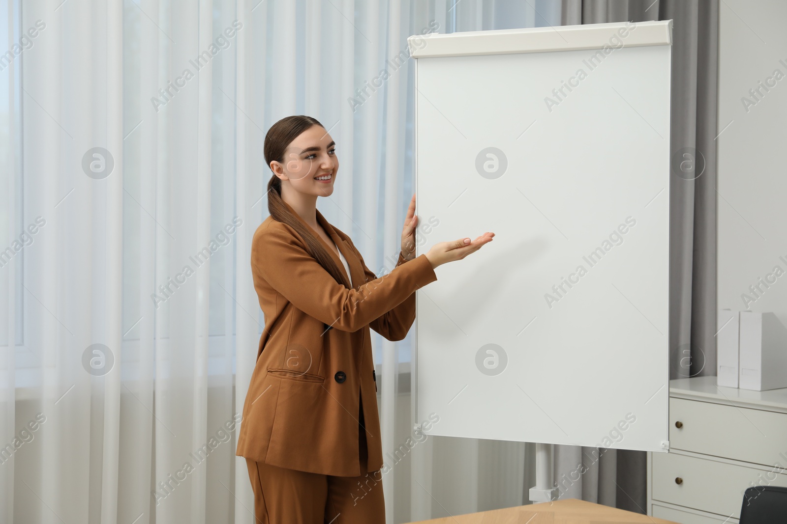 Photo of Happy woman near flip chart in office. Mockup for design