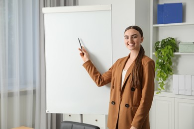 Photo of Happy woman near flip chart in office. Mockup for design