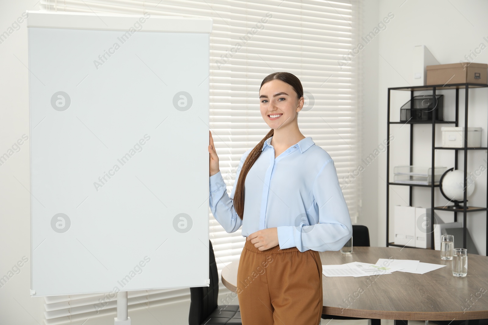 Photo of Happy woman near flip chart in office. Mockup for design