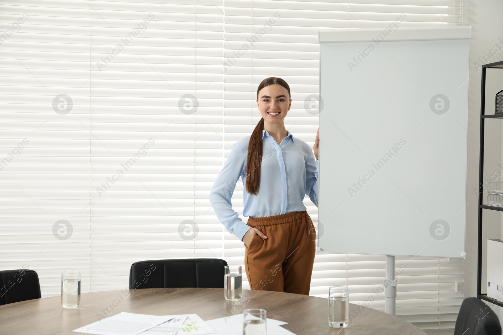 Photo of Happy woman near flip chart in office. Mockup for design