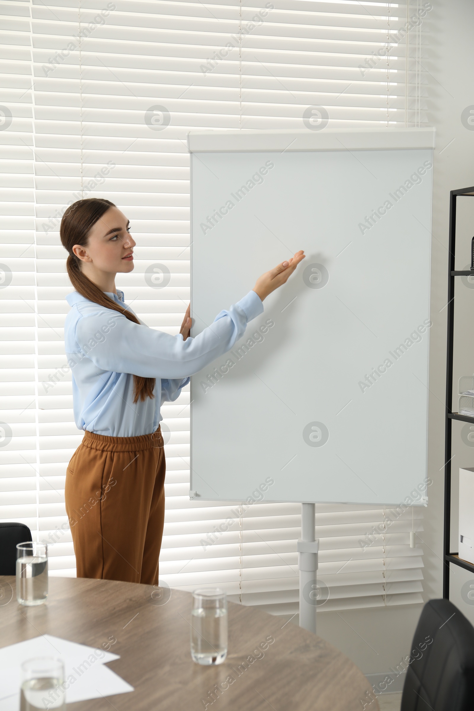 Photo of Happy woman near flip chart in office. Mockup for design