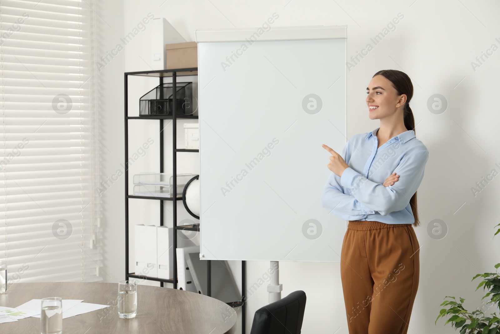 Photo of Happy woman near flip chart in office. Mockup for design